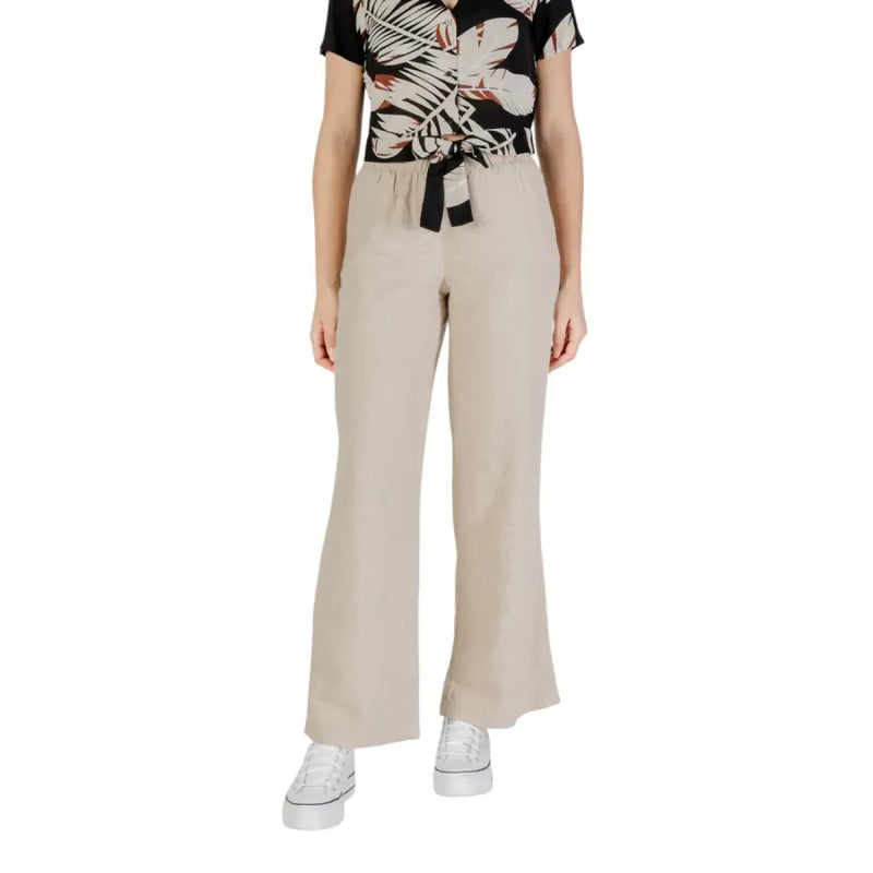 Woman wearing tropical print short-sleeve top beige wide-leg pants and white platform sneakers
