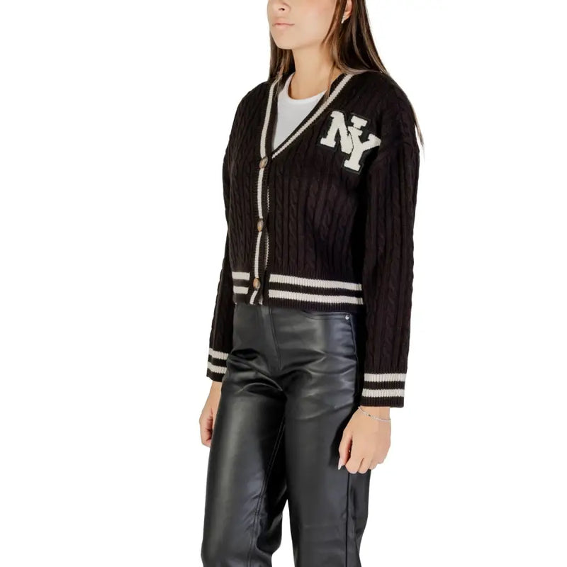 Women’s black cable knit cardigan with white NY emblem and striped trim for fall winter style