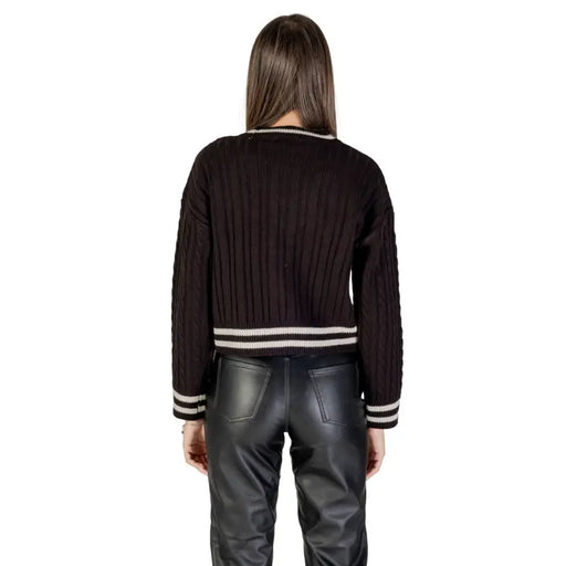 Women’s black ribbed knit cropped cardigan with striped trim paired with black faux leather pants
