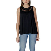 Women’s sleeveless black top with decorative cutout neckline paired with light blue jeans