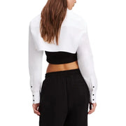 Women wearing a white cropped collared shirt over a black bra top and black pants