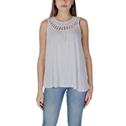 Women’s white sleeveless top with decorative cut-out neckline paired with light blue jeans