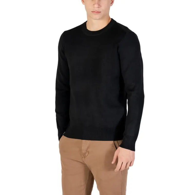 Black crew neck sweater with ribbed cuffs and hem, likely made of cotton or wool.