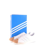 Adidas Baskets en cuir blanc pour homme, style sport, à enfiler, avec bout en liège et design classique à trois bandes.