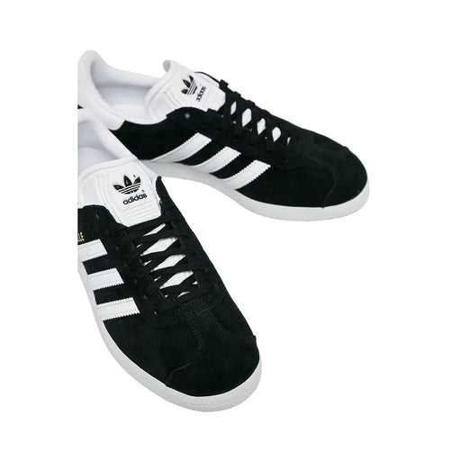 Adidas Baskets noires pour femmes en daim avec semelles en caoutchouc blanc et lacets en polyuréthane à trois bandes.