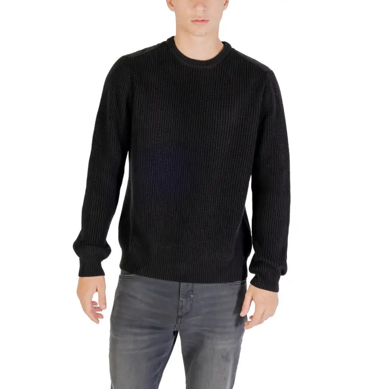 Black ribbed crew neck sweater with long sleeves and a relaxed fit.