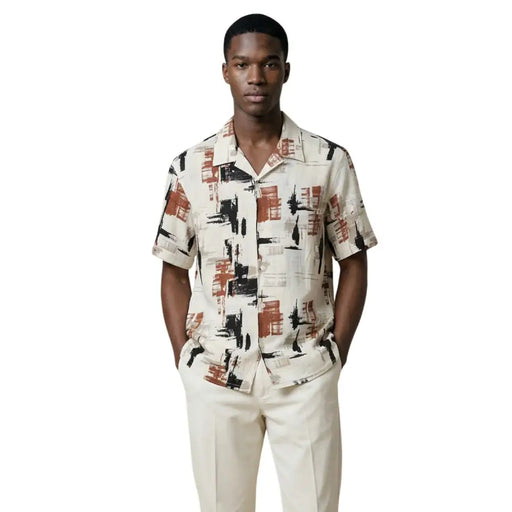 Un homme portant un Antony Morato Chemise homme à manches courtes avec motif géométrique noir et orange rouille sur fond crème