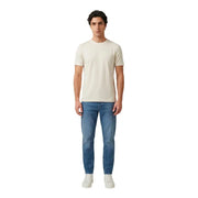 Un homme portant un antony morato hommes t-shirt un t-shirt crème à manches courtes et col rond, porté avec un jean bleu délavé.