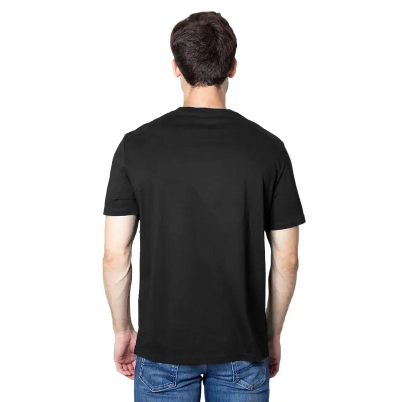 Man wearing Armani Exchange black sleeveless round neck T-shirt and blue jeans from behind