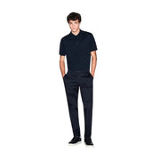Un homme portant un Armani Exchange Polo bleu en coton à manches courtes pour homme, avec un logo brodé discret sur la poitrine.