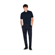 A man wearing an Armani Exchange men blue cotton short sleeve polo shirt with a subtle embroidered logo on the chest
