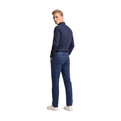 Jean en denim bleu foncé à cinq poches classiques et surpiqûres discrètes, associé à armani exchange chemise en coton bleu à motifs géométriques pour homme