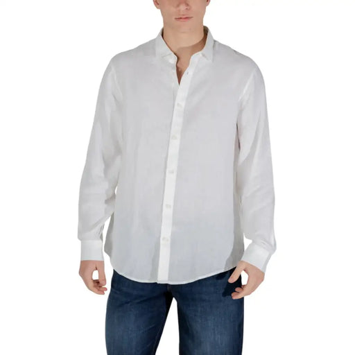 Chemise blanche à manches longues pour homme, portée avec un jean bleu pour un style printemps-été