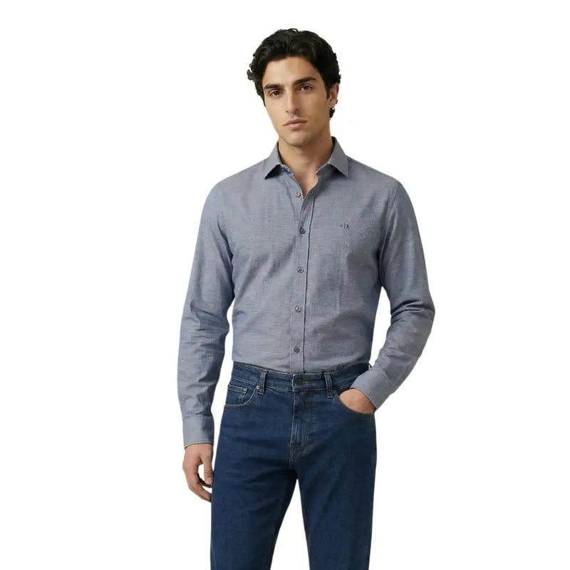 Un homme portant un Armani Exchange Chemise grise texturée à manches longues, boutonnée, avec un motif discret et un logo brodé