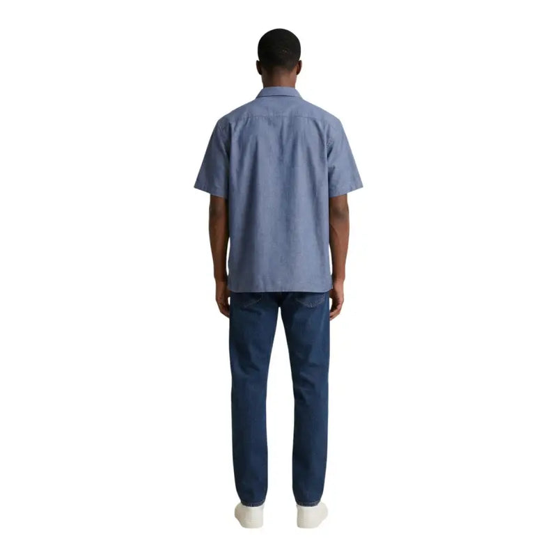 Un homme portant un armani exchange chemise en coton bleu clair à manches courtes et jean en denim foncé