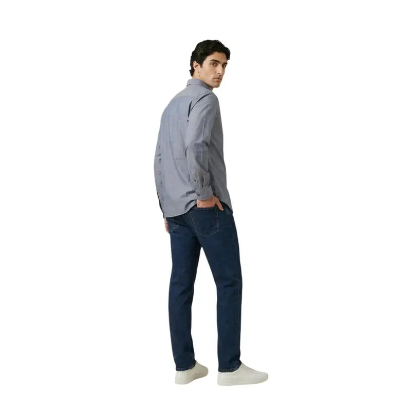 Un homme portant un Armani Exchange chemise homme en coton gris clair à boutons, portée avec un jean bleu foncé