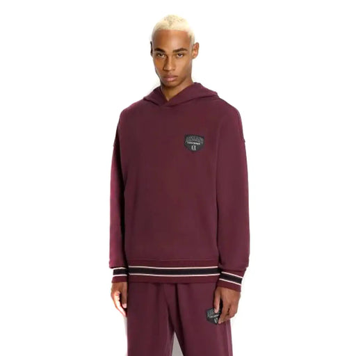 Armani Exchange Sweat-shirt homme bordeaux à capuche avec poche, logo Puma bordeaux et poignets rayés noirs et blancs.