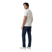 A man wearing an Armani Exchange white cotton t-shirt paired with dark blue denim jeans in a casual style
