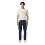 A man wearing an Armani Exchange cream t-shirt with gold maison margiela logo and dark blue denim jeans