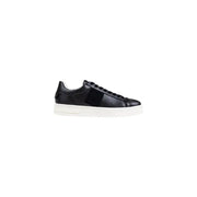 Black leather low-top sneaker with white sole and strap detail.