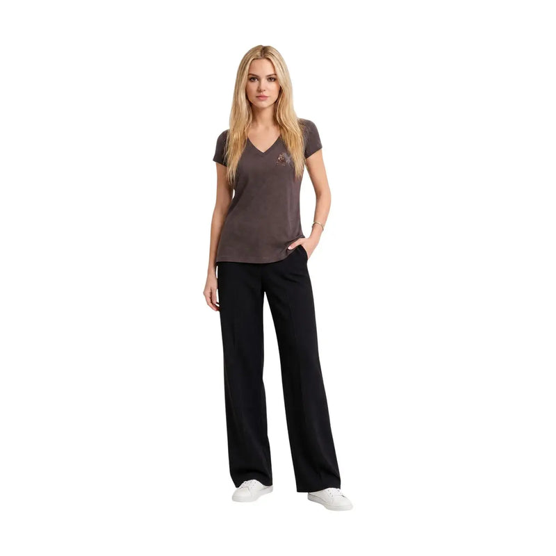 Une femme portant un Armani Exchange T-shirt à paillettes marron en coton à col V pour femme, porté avec un pantalon noir et des baskets blanches.