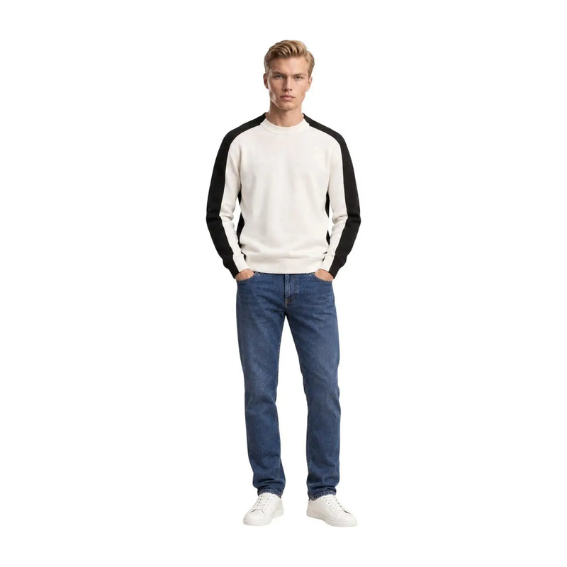 Armani Exchange Pull en laine pour homme, coloris crème et noir, manches raglan et col rond, porté par un mannequin avec un jean bleu.