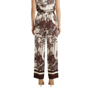 Pantalon large en soie couleur crème, orné d'un imprimé tropical marron audacieux et de revers rayés, issu de la collection printemps-été d'Artigli.