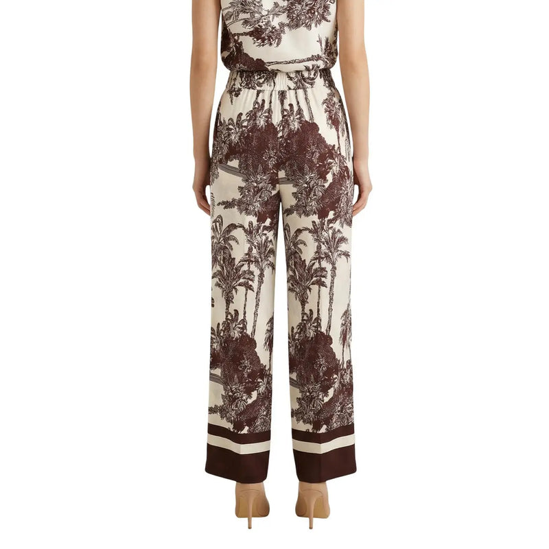 Pantalon large en soie couleur crème, orné d'un imprimé tropical marron audacieux et de revers rayés, issu de la collection printemps-été d'Artigli.