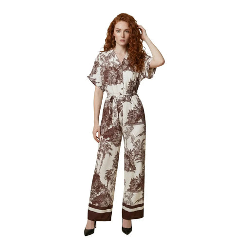 Une femme porte une combinaison Artigli beige en viscose à col en V et imprimé botanique marron, avec une ceinture assortie.