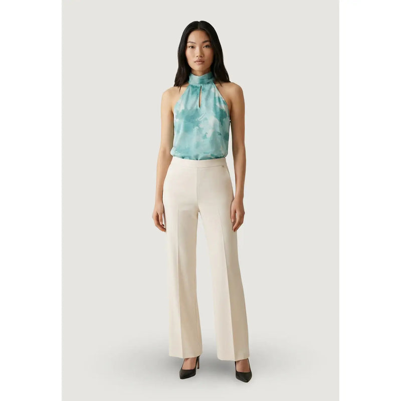 Une femme porte un pantalon blanc à jambes larges Artigli pour femme, avec des poches avant zippées, associé à un haut dos nu turquoise tie-dye. top