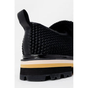 Ash women black leather slip on shoe showing back with black woven design glossy heel tab and striped platform sole