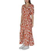 A woman wearing a b.young floral v-neck dress in brown with vibrant orange tropical leaf patterns on 100% viscose