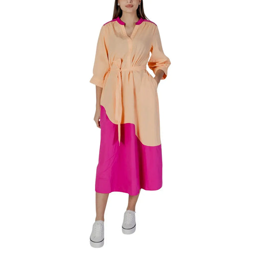 A woman wears a peach and fuchsia color-blocked b.young silver v-neck cotton midi dress with buttons and pockets