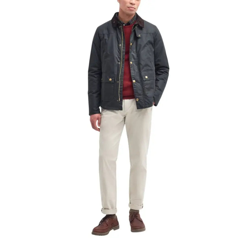 Men’s dark green quilted Barbour jacket with corduroy collar over red sweater and light pants