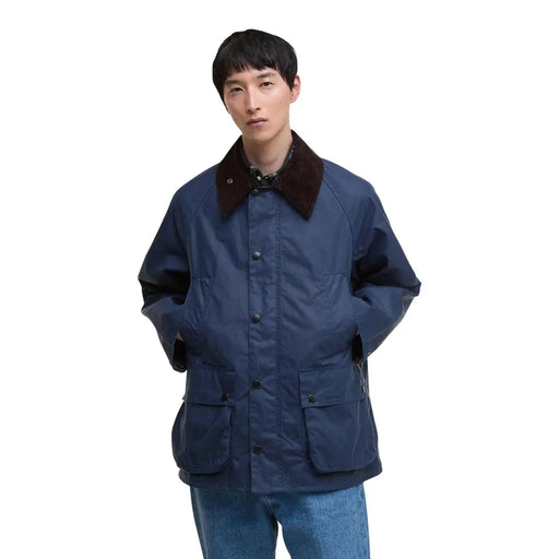 Le blazer Barbour pour homme en coton ciré bleu est une veste de terrain en coton ciré bleu marine avec un col marron foncé et des boutons noirs.