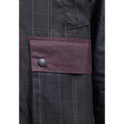 Veste Barbour pour homme en coton ciré marron patchwork avec rabat en tissu bordeaux, bouton argenté et logo brodé sur fond à carreaux gris foncé