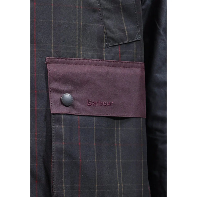 Veste Barbour pour homme en coton ciré marron patchwork avec rabat en tissu bordeaux, bouton argenté et logo brodé sur fond à carreaux gris foncé