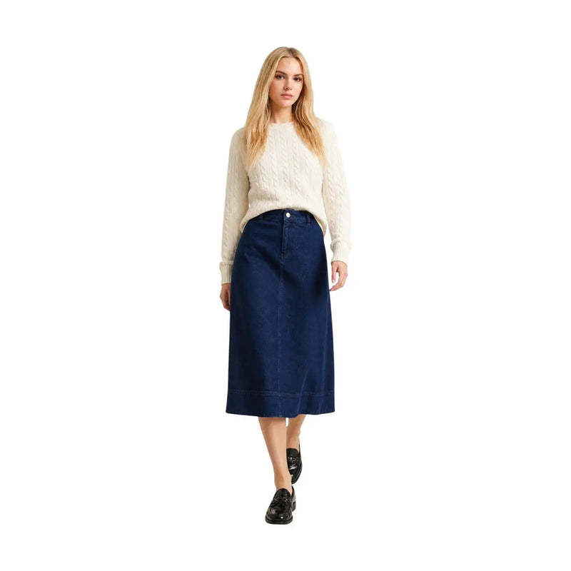 Jupe midi en denim bleu marine à coupe droite et fermeture boutonnée, présentée avec un pull Barbour pour femme en laine et coton blanc cendré.