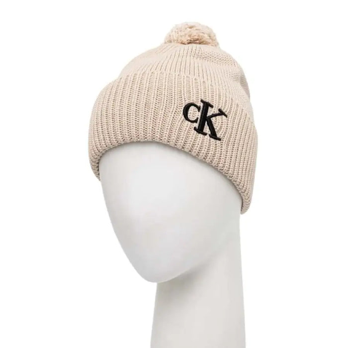 Beige knit beanie with black CK logo and pompom for stylish winter wear