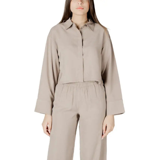 Beige two-piece open back pantsuit displayed as a stylish and elegant womenswear ensemble