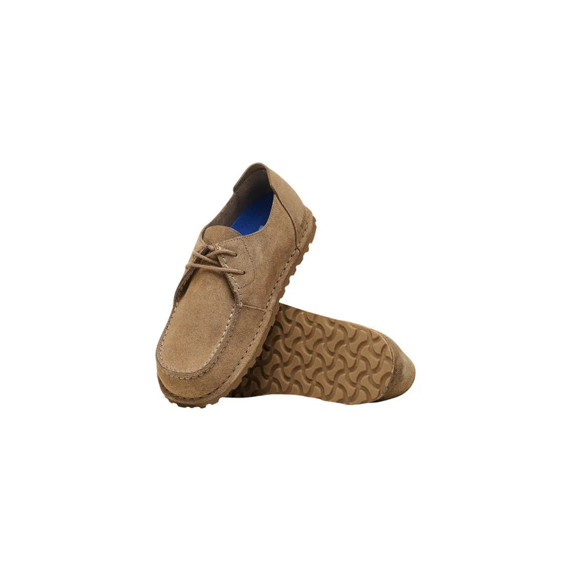 Mocassins Birkenstock pour homme en daim beige, lacés, semelle en caoutchouc texturé et doublure bleue.