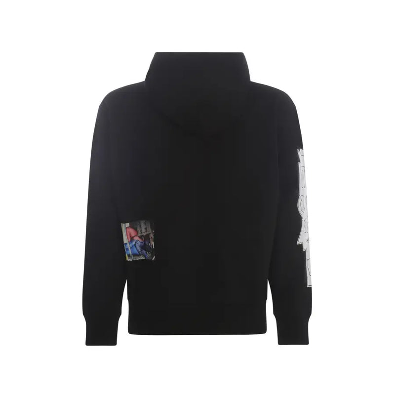 Sweat-shirt à capuche noir avec un petit écusson photo rectangulaire sur la poitrine gauche et un motif graphique blanc sur la manche droite.