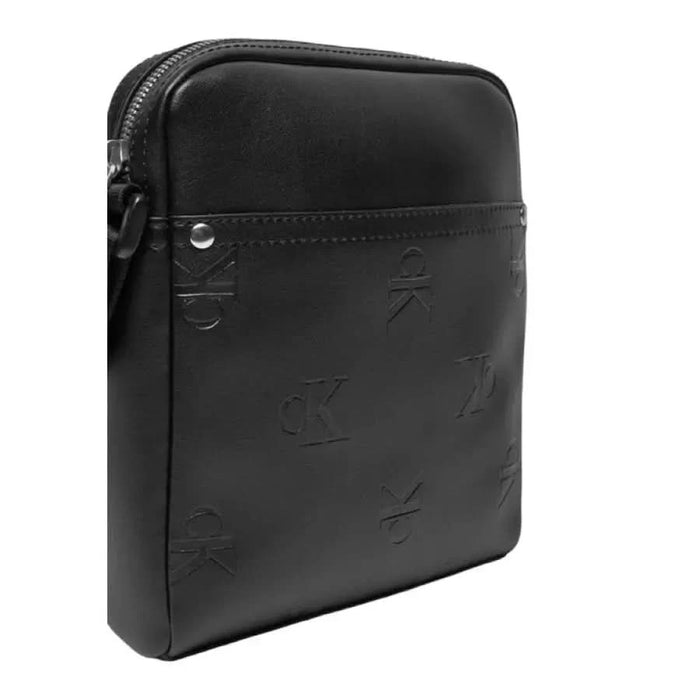 Black leather crossbody bag with embossed pattern and zipper closure by Calvin Klein