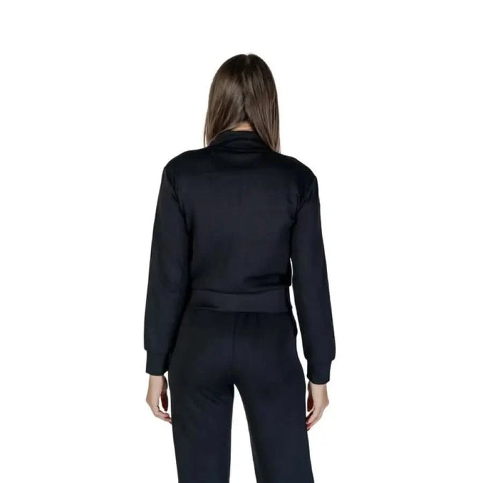 Black long-sleeved athletic jumpsuit displayed from behind in Guess Active product