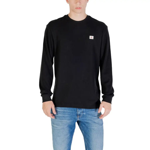 Un homme portant une chemise noire à manches longues et un jean bleu