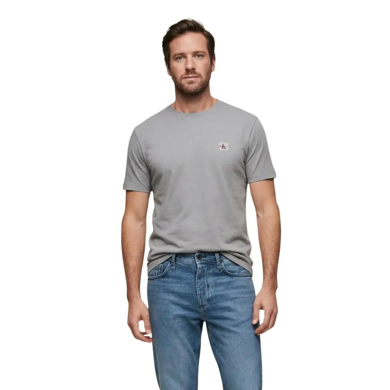 Col rond noir à manches courtes t-shirt en gris avec un petit motif rouge et blanc Calvin Klein logo sur la poitrine gauche