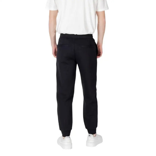 Black sweatpants paired with white sneakers displayed in a product image