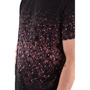 T-shirt noir à manches courtes orné d'un dégradé de sequins roses et blancs évoquant des étoiles et des éclaboussures.