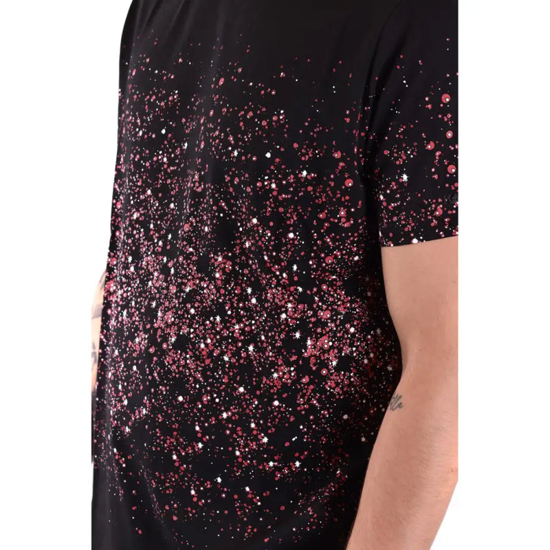 T-shirt noir à manches courtes orné d'un dégradé de sequins roses et blancs évoquant des étoiles et des éclaboussures.