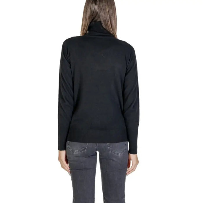 Black turtleneck sweater with side zippers paired with gray jeans for a stylish look